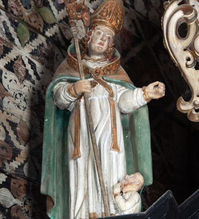 Zdjęcie nr 28: Nastawa ołtarzowa architektoniczna, jednoosiowa, jednokondygnacyjna, z wydzieloną predellą i zwieńczeniem, na cokole. Ołtarz kamienny z narzutem z tynku, sarkofagowy, wklęsło-wypukły. Mensa drewniana z portatylem z marmuru dębnickiego.Predella dekorowana płyciną w formie wydłużonego prostokąta z uszakami z malowanym przedstawieniem Bożego Narodzenia. Nastawa ujęta parą kolumn o kapitelach korynckich podtrzymujących pełne belkowanie belkowanie i gzyms, w części środkowej wyłamane ku górze trójbocznie. W polu środkowym nisza w formie stojącego prostokąta z uszakami, ujęta prostą ramą, wewnątrz gotycka szafa z figurą Matki Boskiej z Dzieciątkiem i czterech świętych dziewic. Na belkowaniu, w osi podpór figury św. Stanisława i św. Marcina (?). W zwieńczeniu ośmioboczny obraz z przedstawieniem Zwiastowania, w prostej ramie oraz bogatym obramieniu z ażurowych motywów ornamentu małżowinowo-chrząstkowego; u szczytu główka aniołka ze skrzydłami. Nastawa flankowana uszami utworzonymi z motywów ornamentu małżowinowo-chrząstkowego. W polu ponad niszą z obrazem rzeźbiona półpostać Boga Ojca. Gzyms u spodu dekorowany ornamentem małżowinowo-chrząstkowym. Struktura polichromowana na czarno, kapitele kolumn i część ornamentów srebrzone, pozostałe motywy ornamentalne złocone.