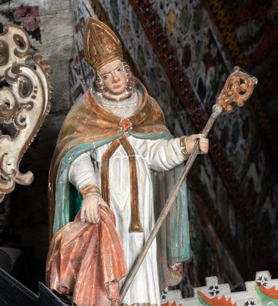 Zdjęcie nr 31: Nastawa ołtarzowa architektoniczna, jednoosiowa, jednokondygnacyjna, z wydzieloną predellą i zwieńczeniem, na cokole. Ołtarz kamienny z narzutem z tynku, sarkofagowy, wklęsło-wypukły. Mensa drewniana z portatylem z marmuru dębnickiego.Predella dekorowana płyciną w formie wydłużonego prostokąta z uszakami z malowanym przedstawieniem Bożego Narodzenia. Nastawa ujęta parą kolumn o kapitelach korynckich podtrzymujących pełne belkowanie belkowanie i gzyms, w części środkowej wyłamane ku górze trójbocznie. W polu środkowym nisza w formie stojącego prostokąta z uszakami, ujęta prostą ramą, wewnątrz gotycka szafa z figurą Matki Boskiej z Dzieciątkiem i czterech świętych dziewic. Na belkowaniu, w osi podpór figury św. Stanisława i św. Marcina (?). W zwieńczeniu ośmioboczny obraz z przedstawieniem Zwiastowania, w prostej ramie oraz bogatym obramieniu z ażurowych motywów ornamentu małżowinowo-chrząstkowego; u szczytu główka aniołka ze skrzydłami. Nastawa flankowana uszami utworzonymi z motywów ornamentu małżowinowo-chrząstkowego. W polu ponad niszą z obrazem rzeźbiona półpostać Boga Ojca. Gzyms u spodu dekorowany ornamentem małżowinowo-chrząstkowym. Struktura polichromowana na czarno, kapitele kolumn i część ornamentów srebrzone, pozostałe motywy ornamentalne złocone.