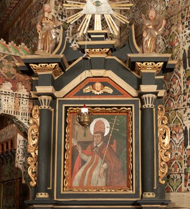 Zdjęcie nr 24: Nastawa ołtarzowa architektoniczna, jednoosiowa, jednokondygnacyjna z wydzieloną predellą i zwieńczeniem. Mensa drewniana. Kondygnacja ujęta parą kolumn o kompozytowych kapitelach podtrzymujących architraw i fryz oraz gzyms, nad polem środkowym formę wyłamane ku górze trójbocznie, występujące w osi podpór. W polu środkowym nisza w formie stojącego prostokąta ujętego prostą ramą; wewnątrz obraz Św. Grzegorz. W polu, ponad obrazem, główka aniołka ze skrzydłami.  W zwieńczeniu Oko Opatrzności w glorii promienistej, flankowane odcinkami przerwanego przyczółka oraz rzeźby Św. Piotr i Św. Andrzej umieszczone w osi podpór. Nastawa ujęta uszami utworzonymi z motywów stylizowanej małżowiny. Cokoły kolumn i predella dekorowane płycinami. Nisza w polu środkowym ujęta ornamentem roślinnym. u spodu fragmenty gzymsu dekorowane ornamentem roślinno-geometrycznym.Struktura polichromowana na czarno, profile srebrzone, motywy ornamentalne złocone. Na odwrocie portatylu napis: ANNO DNI 1761. DIE 7 …. IN ECCLESIA CATHEDRALI HOC ALTARE PORTATILE [CONSECR]ATUM EST AB ILUSTRISSIMO REVENDERISSIMO DOMINO TOMAE ZIENGO EPISCOPO' AREOPOLITANO ET SUFRAGANO RIE ALBAE RUSSIAE CUSTODIE PRAELATIAE CATHEDRALI VILNENSI SECRETARIO MAGNE DUCATI LITHUANIAE CUI IMPOSITAE SUNT RELIQUIAE SANCTORUM EUTYCHII ANDFUANDI ET ALIIS MILIUM MARTYRUM ET QUORAM FIDEN … ET SIGILLO MUNIO.…. Pieczęć z herbem własnym Poniżej herb Zadzika i napis: ANTONIUS ZAUDZI CRAC CAPIT. VOTTO … HOC ALTARE PORTATILE ANNO 1761 CONSECRATUM ANNO 1847 SEPTEMBRIS 16 ILUSTRISSIMO REVENDERISSIMO DOMINO CASEMIRO DMOCHOWSKI EPISCOPO MITTER… SUFFR. CURANIENSE … EQUITE RECTIS ET INVENTIS INTROIS? SACER …FERIBUS RELIQUII SIGILLO EIUSDEM ILUSTRISSIMI EPISCOPI MUNITUM TESOR EGO JACOBUS CAROLEWICZ VICAR. ECCLEIAE CATHEDRALI VILNENSIS ORDINARIUS SANCTI STANISLAI TERIUM CLASSIQUES MPR' [MANU PROPRIAE]