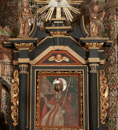 Zdjęcie nr 13: Nastawa ołtarzowa architektoniczna, jednoosiowa, jednokondygnacyjna z wydzieloną predellą i zwieńczeniem. Mensa drewniana. Kondygnacja ujęta parą kolumn o kompozytowych kapitelach podtrzymujących architraw i fryz oraz gzyms, nad polem środkowym formę wyłamane ku górze trójbocznie, występujące w osi podpór. W polu środkowym nisza w formie stojącego prostokąta ujętego prostą ramą; wewnątrz obraz Św. Grzegorz. W polu, ponad obrazem, główka aniołka ze skrzydłami.  W zwieńczeniu Oko Opatrzności w glorii promienistej, flankowane odcinkami przerwanego przyczółka oraz rzeźby Św. Piotr i Św. Andrzej umieszczone w osi podpór. Nastawa ujęta uszami utworzonymi z motywów stylizowanej małżowiny. Cokoły kolumn i predella dekorowane płycinami. Nisza w polu środkowym ujęta ornamentem roślinnym. u spodu fragmenty gzymsu dekorowane ornamentem roślinno-geometrycznym.Struktura polichromowana na czarno, profile srebrzone, motywy ornamentalne złocone. Na odwrocie portatylu napis: ANNO DNI 1761. DIE 7 …. IN ECCLESIA CATHEDRALI HOC ALTARE PORTATILE [CONSECR]ATUM EST AB ILUSTRISSIMO REVENDERISSIMO DOMINO TOMAE ZIENGO EPISCOPO&#039; AREOPOLITANO ET SUFRAGANO RIE ALBAE RUSSIAE CUSTODIE PRAELATIAE CATHEDRALI VILNENSI SECRETARIO MAGNE DUCATI LITHUANIAE CUI IMPOSITAE SUNT RELIQUIAE SANCTORUM EUTYCHII ANDFUANDI ET ALIIS MILIUM MARTYRUM ET QUORAM FIDEN … ET SIGILLO MUNIO.…. Pieczęć z herbem własnym Poniżej herb Zadzika i napis: ANTONIUS ZAUDZI CRAC CAPIT. VOTTO … HOC ALTARE PORTATILE ANNO 1761 CONSECRATUM ANNO 1847 SEPTEMBRIS 16 ILUSTRISSIMO REVENDERISSIMO DOMINO CASEMIRO DMOCHOWSKI EPISCOPO MITTER… SUFFR. CURANIENSE … EQUITE RECTIS ET INVENTIS INTROIS? SACER …FERIBUS RELIQUII SIGILLO EIUSDEM ILUSTRISSIMI EPISCOPI MUNITUM TESOR EGO JACOBUS CAROLEWICZ VICAR. ECCLEIAE CATHEDRALI VILNENSIS ORDINARIUS SANCTI STANISLAI TERIUM CLASSIQUES MPR&#039; [MANU PROPRIAE]