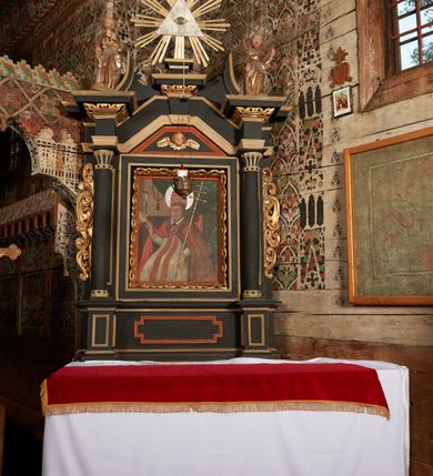 Zdjęcie nr 2: Nastawa ołtarzowa architektoniczna, jednoosiowa, jednokondygnacyjna z wydzieloną predellą i zwieńczeniem. Mensa drewniana. Kondygnacja ujęta parą kolumn o kompozytowych kapitelach podtrzymujących architraw i fryz oraz gzyms, nad polem środkowym formę wyłamane ku górze trójbocznie, występujące w osi podpór. W polu środkowym nisza w formie stojącego prostokąta ujętego prostą ramą; wewnątrz obraz Św. Grzegorz. W polu, ponad obrazem, główka aniołka ze skrzydłami.  W zwieńczeniu Oko Opatrzności w glorii promienistej, flankowane odcinkami przerwanego przyczółka oraz rzeźby Św. Piotr i Św. Andrzej umieszczone w osi podpór. Nastawa ujęta uszami utworzonymi z motywów stylizowanej małżowiny. Cokoły kolumn i predella dekorowane płycinami. Nisza w polu środkowym ujęta ornamentem roślinnym. u spodu fragmenty gzymsu dekorowane ornamentem roślinno-geometrycznym.Struktura polichromowana na czarno, profile srebrzone, motywy ornamentalne złocone. Na odwrocie portatylu napis: ANNO DNI 1761. DIE 7 …. IN ECCLESIA CATHEDRALI HOC ALTARE PORTATILE [CONSECR]ATUM EST AB ILUSTRISSIMO REVENDERISSIMO DOMINO TOMAE ZIENGO EPISCOPO' AREOPOLITANO ET SUFRAGANO RIE ALBAE RUSSIAE CUSTODIE PRAELATIAE CATHEDRALI VILNENSI SECRETARIO MAGNE DUCATI LITHUANIAE CUI IMPOSITAE SUNT RELIQUIAE SANCTORUM EUTYCHII ANDFUANDI ET ALIIS MILIUM MARTYRUM ET QUORAM FIDEN … ET SIGILLO MUNIO.…. Pieczęć z herbem własnym Poniżej herb Zadzika i napis: ANTONIUS ZAUDZI CRAC CAPIT. VOTTO … HOC ALTARE PORTATILE ANNO 1761 CONSECRATUM ANNO 1847 SEPTEMBRIS 16 ILUSTRISSIMO REVENDERISSIMO DOMINO CASEMIRO DMOCHOWSKI EPISCOPO MITTER… SUFFR. CURANIENSE … EQUITE RECTIS ET INVENTIS INTROIS? SACER …FERIBUS RELIQUII SIGILLO EIUSDEM ILUSTRISSIMI EPISCOPI MUNITUM TESOR EGO JACOBUS CAROLEWICZ VICAR. ECCLEIAE CATHEDRALI VILNENSIS ORDINARIUS SANCTI STANISLAI TERIUM CLASSIQUES MPR' [MANU PROPRIAE]