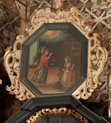 Zdjęcie nr 5: Retabulum ołtarzowe z dużą rzeźbą Matki Boskiej z Dzieciątkiem oraz mniejszymi o połowę czterema rzeźbami Świętych Dziewic umieszczonymi w prostopadłościennej szafie na rzucie trapezu (z ukośnie ustawionymi ściankami bocznymi). Rzeźby pełnoplastyczne, ścięte z tyłu, drążone, ustawione na cokolikach. Pośrodku figura Matki Boskiej w stylu gotyku międzynarodowego; zwrócona en face, w delikatnym kontrapoście, o esowato wygiętej sylwetce, podtrzymuje na obu rękach wpółleżące Dzieciatko. Twarz owalna z podwójnym podbródkiem, rysy twarzy płytko rzeźbione, delikatne, długi, prosty nos. Włosy upięte z tyłu. Maria ubrana w srebrzoną suknię z tkaniną drapowaną po środku w trzy fałdy misowe oraz złocony płaszcz podbity na niebieską podszewką, spływający od tyłu głowy na ramiona i boki, w układzie kaskadowym. Na głowie korona otwarta. Dzieciatko wpółleżące, zwrócone en trois quarts w prawo, prawą ręka ujmuje Matkę za szyję, w lewej trzyma złotą kulę. Twarz okrągła, duże uszy, włosy krótkie, kręcone. W partii bioder przepasany ściśle przylegającą, złotą tkaniną, delikatnie drapowaną. Na lewej ściance szafy u góry figurka św. Cecylii, zwróconej en face, o esowato wygiętej sylwetce, w lewej ręce, opartej na biodrze trzyma piszczałki, prawa wyciągnięta do przodu. Twarz okrągła o pełnych policzkach i płytko rzeźbionych rysach twarzy, włosy długie, falujące fakturowane, spływające przez ramiona na plecy. Ubrana w srebrzoną suknię oraz złocony płaszcz z czerwoną podszewką, spięty na piersi fibulą, z obfitą draperią przewieszoną przez ramiona, opadająca na froncie fałdami misowymi oraz spływającymi kaskadami od ramion. Na głowie blok drewna z namalowaną koroną otwartą.Na lewej ściance u dołu figura św. Katarzyny Aleksandryjskiej, zwróconej en face, w prawej ręce podtrzymuje koło, lewą wyciąga do przodu. Twarz okrągła, policzki pełne, o wysokim czole, nos duży, oczy duże delikatnie zarysowane. Włosy falowane, fakturowane, spływają na plecy. Święta ubrana w srebrzona suknię przepasaną w talii oraz złocony płaszcz spięty broszą na piersi, z obfitą draperią przewieszoną przez ramiona, opadająca na froncie misowymi fałdami i spływającymi kaskadami od ramion. Na głowie blok drewna z namalowaną koroną otwartą. Na prawej ściance u góry figura św. Doroty, zwrócona en face w delikatnym kontrapoście, prawa ręką podtrzymuje koszyk, lewą wskazuje na niego. Twarz owalna, pełna, delikatne rysy, wąski zadarty nos. Włosy falowane, fakturowane, opadają na tył głowy. Ubrana w złotą suknię, delikatnie drapowaną u dołu, oraz srebrzony płaszcz podbity czerwoną podszewką, spięty na piersi i układający się z przodu w fałdy misowe. Na głowie blok drewna z namalowaną koroną otwartą. Na prawej ściance u dołu figura św. Barbary, zwróconej en face, o esowato przegiętej sylwetce, obiema rękami przytrzymuje opartą na lewym ramieniu wieżę. Twarz owalna, pełna, delikatne rysy, wąski zadarty nos. Włosy falowane, fakturowane, opadają na tył głowy. Ubrana w suknię i srebrzony płaszcz z niebieską podszewką, spięty na piersi fibulą, przerzucony przez ramiona z obfitą partią materiału układającą się z przodu w fałdy misowe. Na głowie blok drewna z namalowaną koroną otwartą. Karnacje w tonacji naturalnej, szaty srebrzone i złocone.