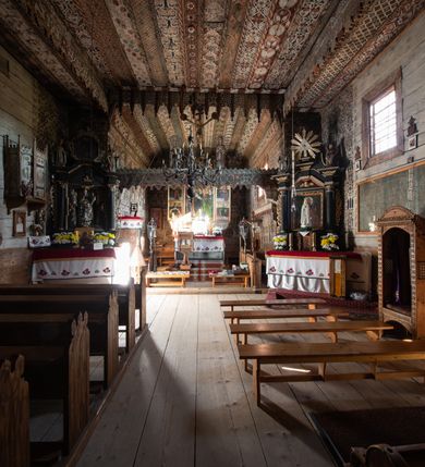 Zdjęcie nr 13: Polichromia pokrywa strop i ściany prezbiterium, strop, zaskrzynienia i ściany nawy oraz belkę tęczową, ambonę, ławkę kolatorską i parapet chóru muzycznego.  W dekoracji zastosowano 77 motywów zarówno figuralnych, jak i  heraldycznych, roślinnych, zwierzęcych, sakralnych, architektonicznych, tekstylnych, geometrycznych. Motywy tworzą oddzielne pasy dekoracyjne , dając wrażenie wzorzystych tkanin lub fryzów. Koloryt: jasna i ciemna czerwień, zielenie, błękity, brązy oraz żółcienie na białym lub czarnym podkładzie, czasem bezpośrednio na drewnie.  