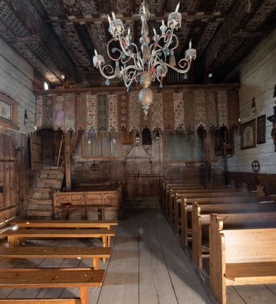 Zdjęcie nr 21: Polichromia pokrywa strop i ściany prezbiterium, strop, zaskrzynienia i ściany nawy oraz belkę tęczową, ambonę, ławkę kolatorską i parapet chóru muzycznego.  W dekoracji zastosowano 77 motywów zarówno figuralnych, jak i  heraldycznych, roślinnych, zwierzęcych, sakralnych, architektonicznych, tekstylnych, geometrycznych. Motywy tworzą oddzielne pasy dekoracyjne , dając wrażenie wzorzystych tkanin lub fryzów. Koloryt: jasna i ciemna czerwień, zielenie, błękity, brązy oraz żółcienie na białym lub czarnym podkładzie, czasem bezpośrednio na drewnie.  