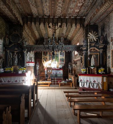 Zdjęcie nr 23: Polichromia pokrywa strop i ściany prezbiterium, strop, zaskrzynienia i ściany nawy oraz belkę tęczową, ambonę, ławkę kolatorską i parapet chóru muzycznego.  W dekoracji zastosowano 77 motywów zarówno figuralnych, jak i  heraldycznych, roślinnych, zwierzęcych, sakralnych, architektonicznych, tekstylnych, geometrycznych. Motywy tworzą oddzielne pasy dekoracyjne , dając wrażenie wzorzystych tkanin lub fryzów. Koloryt: jasna i ciemna czerwień, zielenie, błękity, brązy oraz żółcienie na białym lub czarnym podkładzie, czasem bezpośrednio na drewnie.  