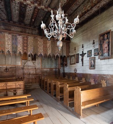 Zdjęcie nr 24: Polichromia pokrywa strop i ściany prezbiterium, strop, zaskrzynienia i ściany nawy oraz belkę tęczową, ambonę, ławkę kolatorską i parapet chóru muzycznego.  W dekoracji zastosowano 77 motywów zarówno figuralnych, jak i  heraldycznych, roślinnych, zwierzęcych, sakralnych, architektonicznych, tekstylnych, geometrycznych. Motywy tworzą oddzielne pasy dekoracyjne , dając wrażenie wzorzystych tkanin lub fryzów. Koloryt: jasna i ciemna czerwień, zielenie, błękity, brązy oraz żółcienie na białym lub czarnym podkładzie, czasem bezpośrednio na drewnie.  