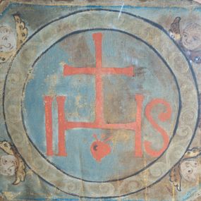 Zdjęcie nr 1: W kształcie wydłużonego ośmioboku o czterech przeciwległych (po przekątnej) bokach wklęsłych. Pośrodku na błękitnym tle duży kolisty medalion, w polu którego duże czerwone litery IHS z krzyżem oraz motywem serca poniżej. Obramienie medalionu wypełnione motywem wolut. Wokół medalionu główki aniołków ze skrzydłami. Kolorystyka pociemniała. 