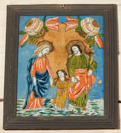 Zdjęcie nr 6: Obraz w kształcie stojącego prostokąta, w starszej, drewnianej, profilowanej ramce pomalowanej na czarno. Na błękitnym jednolitym tle całopostaciowe przedstawienie Matki Boskiej i św. Józefa prowadzących za ręce kilkuletniego Jezusa.   Postacie zwrócone w trzech czwartych w lewo, ukazane w ruchu (w wykroku). Maria ubrana w długą czerwoną suknię, okryta ciemnoniebieskim płaszczem, na głowie nosi białą chustę. Św. Józef, ubrany w długą zieloną suknię, przewiązany w pasie czerwoną draperią, w lewej dłoni trzyma białą lilię, głowę zwraca w kierunku idącego obok Jezusa. Wokół głów Marii i Józefa koliste nimby.  W tle, za plecami przedstawionych osób duże złote koło ozdobione w górnej części dużymi kielichami kwiatów róż i tulipanów. Koloryt intensywny, nasycony. Formy kształtowane czarnym konturem i światłocieniowo.