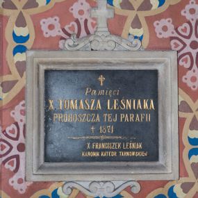 Zdjęcie nr 1: Tablica z czarnego marmuru w formie leżącego prostokąta, ujęta profilowaną ramą z piaskowca, zwieńczoną wolutowym szczytem z krzyżem. W polu inskrypcja „Pamięci / X(IĘDZA) TOMASZA LEŚNIAKA / PROBOSZCZA TEJ PARAFII / + 1871 / X(IĘDZA) FRANCISZEK LEŚNIAK / KANONIK KATEDR(Y) TARNOWSKIEJ”.
