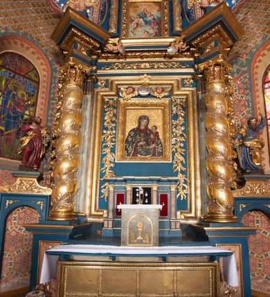 Zdjęcie nr 4: Nastawa architektoniczna, jednoosiowa z bramkami, jednokondygnacyjna ze zwieńczeniem, na wysokim cokole z wyłamanymi dwoma prostopadłościanami. Ołtarz skrzyniowy, prostopadłościenny, obity blachą; mensa drewniana. Na ołtarzu tabernakulum i tron wystawienia. Nastawa flankowana parą pilastrów i ustawioną przed nimi parą kolumn o kręconych trzonach oplecionych wicią roślinną, z korynckimi kapitelami. Podpory dźwigają pełne belkowanie wyłamane pod kątem na ich osi, z fryzem dekorowanym rozetami i wicią roślinną oraz cokoły z figurami puttów na obłokach. Niemal całe pole środkowe wypełnione wnęką w formie stojącego prostokąta o wciętych górnych narożach, ujętą profilowaną ramą. Wewnątrz dużo mniejszy obraz Matki Boskiej Gajowskiej w osobnej ramie, flankowany roślinnymi zwisami, od góry dekorowany uskrzydlonymi główkami anielskimi na obłokach. Nastawa ujęta uszami w kształcie roślinnych zwisów. Zwieńczenie w formie stojącego prostokąta, flankowane kolumienkami o kręconych trzonach oraz spływami wolutowymi. Podpory dźwigają pełne belkowanie wyłamane na ich osi, dekorowane rozetami i uskrzydloną główką anielską oraz fragmenty przerwanego półkolistego przyczółka. Na belkowaniu cokół z figurą anioła. Całe pole wypełnia wnęka w formie stojącego prostokąta ujętego ramą dekorowaną ornamentem roślinnym, z obrazem Matki Boskiej Anielskiej. Nastawę flankują bramki w profilowanych framugach, z przejściami w kształcie stojącego prostokąta zamkniętego łukiem półkolistym, w przyłuczach dekorowane ornamentem roślinnym. Zamknięte są cokołami utworzonymi ze spływów wolutowych, na których stoją figury św. Piotra i św. Pawła. Struktura polichromowana w kolorze niebiesko-zielonym, z czerwonymi detalami; kolumny, profile i ornamentyka złocone. 
