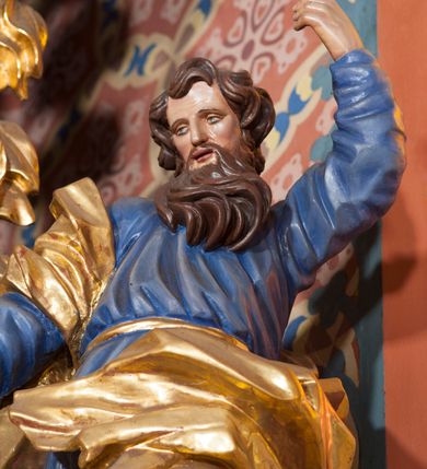 Zdjęcie nr 4: Pełnoplastyczna rzeźba ustawiona na nieregularnej podstawie. Święty ukazany frontalnie, w kontrapoście, z ugiętą lewą nogą oraz pochyloną głową. Lewą rękę unosi wysoko, z wskazującym gestem dłoni, prawą wyciąga w dół, w dłoni trzyma srebrzony miecz, skierowany ostrzem w dół. Twarz ma pociągłą, szczupłą, o migdałowatych oczach, dużym nosie i rozchylonych, pełnych ustach. Okolona jest gęstą, skręconą brodą opadającą na pierś oraz krótkimi, falistymi włosami. Święty ubrany jest w niebieską tunikę, przylegającą do ciała i silnie drapowaną, przepasaną w talii oraz złocony płaszcz przewiązany przez prawe ramię i zawinięty na lewej nodze, na stopach ma złocone buty. Polichromia ciała naturalistyczna.
