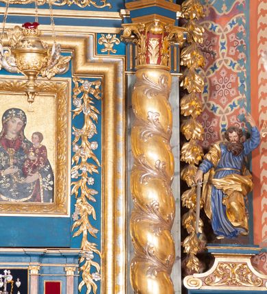 Zdjęcie nr 6: Pełnoplastyczna rzeźba ustawiona na nieregularnej podstawie. Święty ukazany frontalnie, w kontrapoście, z ugiętą lewą nogą oraz pochyloną głową. Lewą rękę unosi wysoko, z wskazującym gestem dłoni, prawą wyciąga w dół, w dłoni trzyma srebrzony miecz, skierowany ostrzem w dół. Twarz ma pociągłą, szczupłą, o migdałowatych oczach, dużym nosie i rozchylonych, pełnych ustach. Okolona jest gęstą, skręconą brodą opadającą na pierś oraz krótkimi, falistymi włosami. Święty ubrany jest w niebieską tunikę, przylegającą do ciała i silnie drapowaną, przepasaną w talii oraz złocony płaszcz przewiązany przez prawe ramię i zawinięty na lewej nodze, na stopach ma złocone buty. Polichromia ciała naturalistyczna.
