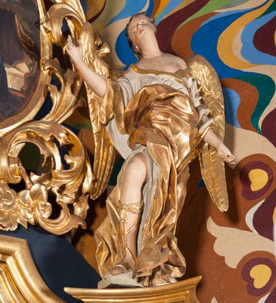 Zdjęcie nr 5: Nastawa ołtarzowa architektoniczna, jednoosiowa, jednokondygnacyjna ze zwieńczeniem. Ołtarz sarkofagowy, wybrzuszony w górnej części, zwężający się ku dołowi, na cokole; mensa drewniana. Na frontowej ścianie skrzyni ołtarzowej płycina w formie odwróconego trapezu. Nastawa ustawiona na dwustrefowym cokole, z wyłamanymi dwoma prostopadłościanami, ujęta parą kolumn o kręconych trzonach oplecionych wicią roślinną, dźwigających fragmenty gzymsu wyłamane pod kątem o wklęsłych bokach. Na nich ustawione figury dwóch aniołów. Niemal całe pole główne wypełnione jest wnęką w formie stojącego prostokąta o wklęsłych górnych narożach, z uskokiem, ujętą grubą, profilowaną ramą dekorowaną kwiatami, z obrazem Matki Boskiej Różańcowej. Pod wnęką płycina wypełniona kwiatami. Kondygnacja flankowana uszami utworzonymi z suchego akantu z dwiema parami puttów. Zwieńczenie w formie medalionu z obrazem Zwiastowania ujętego suchym akantem, zakończone cokołem z figurą anioła. Struktura polichromowana w kolorze niebieskim; kolumny, profile i ornamentyka złocone. 