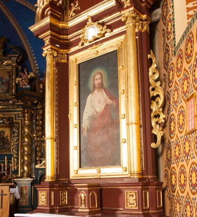 Zdjęcie nr 3: Nastawa architektoniczna, jednoosiowa, jednokondygnacyjna ze zwieńczeniem, ustawiona na dwustrefowym cokole z wyodrębnionymi dwoma prostopadłościanami. Ołtarz sarkofagowy, wybrzuszony w górnej części i zwężający się ku dołowi, na cokole; mensa drewniana. Na frontowej ścianie skrzyni ołtarzowej płycina w formie odwróconego trapezu dekorowana malowaną winną latoroślą na brązowo-zielonym tle. Na ołtarzu tabernakulum w formie drewnianej skrzynki, o ściętych narożach, ustawione na profilowanym cokole, zamknięte gzymsem. Ścianki dekorowane płycinami. Drzwiczki w formie stojącego prostokąta zamkniętego łukiem półkolistym nadwieszonym, z przedstawieniem kielicha z hostią. Nastawa ujęta parą kolumn dźwigających pełne belkowanie wyłamane na ich osi, z fryzem dekorowanym rozetami i kartuszem oraz fragmenty przerwanego półkolistego przyczółka z figurami puttów. Niemal całe pole środkowe wypełnione jest wnęką w formie stojącego prostokąta, ujętego grubą ramą dekorowaną rozetami, z obrazem Najświętszego Serca Jezusa. Zwieńczenie w formie zbliżonej do trapezu, o wklęsłych bokach, zamknięte wolutami i muszlą. W polu obraz Zwiastowania w formie stojącego owalu, ujęty profilowaną ramą, dekorowany naokoło ornamentem roślinnym. Struktura polichromowana w kolorze brązowo-czerwonym; kolumny, profile i ornamentyka złocone. 