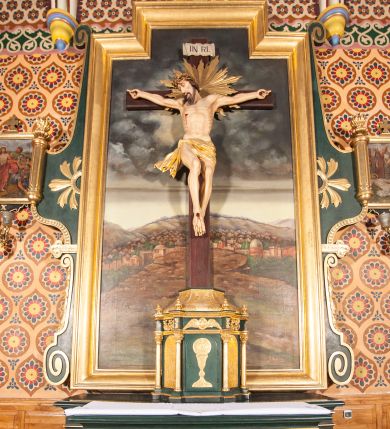 Zdjęcie nr 1: Nastawa niearchitektoniczna, ramowa, ustawiona na wysokim cokole. Ołtarz sarkofagowy, wybrzuszony w górnej części, zwężający się ku dołowi, na cokole; mensa drewniana. Na frontowej ścianie skrzyni ołtarzowej płycina w formie odwróconego trapezu dekorowana malowaną winną latoroślą na ciemnoczerwonym tle. Na ołtarzu ustawione tabernakulum w formie drewnianej skrzynki na planie połowy ośmioboku, wydzielone kolumienkami na cokołach, dźwigającymi pełne belkowanie o fryzie dekorowanym uskrzydloną główką anielską i ornamentem roślinnym. Na ściankach płyciny w kształcie stojącego prostokąta zamkniętego łukiem półkolistym wypełnione rytym ornamentem roślinnym. Drzwiczki o tej samej formie z rytym przedstawieniem kielicha z hostią w glorii. Tabernakulum zwieńczone tronem wystawienia w kształcie wklęsło-wypukłego cokołu, zwężającego się ku górze. Nastawa w formie stojącego prostokąta o wciętych górnych narożach, ujęta profilowaną ramą, z uszakami w formie spływów wolutowych z wyodrębnionymi zwojami dekorowanymi ornamentem roślinnym; zwieńczona rocaille'owym kartuszem. W polu figura Chrystusa Ukrzyżowanego przybita do prostego krzyża, ukazanego na tle malowanej panoramy Jerozolimy, w której prawym dolnym roku znajduje się sygnatura „S(tanisław) Karas / 1913”. 



