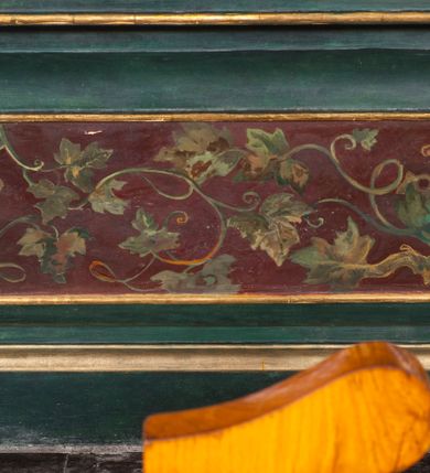 Zdjęcie nr 6: Nastawa niearchitektoniczna, ramowa, ustawiona na wysokim cokole. Ołtarz sarkofagowy, wybrzuszony w górnej części, zwężający się ku dołowi, na cokole; mensa drewniana. Na frontowej ścianie skrzyni ołtarzowej płycina w formie odwróconego trapezu dekorowana malowaną winną latoroślą na ciemnoczerwonym tle. Na ołtarzu ustawione tabernakulum w formie drewnianej skrzynki na planie połowy ośmioboku, wydzielone kolumienkami na cokołach, dźwigającymi pełne belkowanie o fryzie dekorowanym uskrzydloną główką anielską i ornamentem roślinnym. Na ściankach płyciny w kształcie stojącego prostokąta zamkniętego łukiem półkolistym wypełnione rytym ornamentem roślinnym. Drzwiczki o tej samej formie z rytym przedstawieniem kielicha z hostią w glorii. Tabernakulum zwieńczone tronem wystawienia w kształcie wklęsło-wypukłego cokołu, zwężającego się ku górze. Nastawa w formie stojącego prostokąta o wciętych górnych narożach, ujęta profilowaną ramą, z uszakami w formie spływów wolutowych z wyodrębnionymi zwojami dekorowanymi ornamentem roślinnym; zwieńczona rocaille&#039;owym kartuszem. W polu figura Chrystusa Ukrzyżowanego przybita do prostego krzyża, ukazanego na tle malowanej panoramy Jerozolimy, w której prawym dolnym roku znajduje się sygnatura „S(tanisław) Karas / 1913”. 



