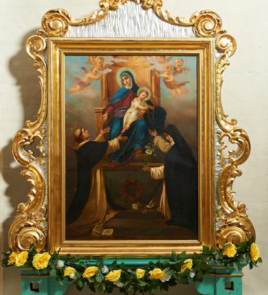 Zdjęcie nr 2: Feretron w formie stojącego prostokąta, w profilowanej ramie, ujęty spływami wolutowymi, zakończony szczytem, dekorowany rocaille'm, pola zdobione falistymi żłobkami. Rama ustawiona na listwie i dwóch cokołach, o profilowanych brzegach, z otworami na drążki. 
Na awersie obraz z Matką Boską Różańcową oraz św. Dominikiem i św. Katarzyną Sieneńską w formie stojącego prostokąta. Matka Boska w centrum kompozycji ukazana jako siedząca na tronie, na wysokim postumencie, z Dzieciątkiem na lewym kolanie. Maria przedstawiona frontalnie, przechylona w prawo, prawą ręką podaje różaniec św. Dominikowi, lewą przytrzymuje Dzieciątko. Ubrana jest w czerwoną suknię i niebieski płaszcz z fioletową podszewką, okalający głowę, spięty pod szyją, opadający na ramiona i kolana. Dzieciątko zwrócone w trzech czwartych w prawo, z tułowiem i głową skręconą w drugą stronę, lekko pochylone podaje oburącz różaniec św. Katarzynie. Ubrane jest w białą tunikę przepasaną w talii. W lewym dolnym rogu postać klęczącego św. Dominika, zwróconego profilem w stronę Matki Boskiej, z wyciągniętymi w górę rękami, w których trzyma różaniec, z uniesioną głową. Święty ubrany jest w biały habit i czarny płaszcz, na głowie ma tonsurę. W prawym dolnym rogu obrazu postać klęczącej św. Katarzyny Sieneńskiej, zwróconej profilem ku Marii, z pochyloną głową, w prawej uniesionej ręce trzyma różaniec, w lewej gałązkę lilii. Ubrana jest w biały habit i czarny płaszcz, na głowie ma czarny welon i koronę cierniową. Pomiędzy świętymi, na cokole wieniec z czerwonych róż i leżąca biała lilia. U nóg św. Dominika otwarta księga. Scenę ukazana na tle błękitno-różowego nieba z obłokami. Tron ujęty dwoma aniołkami i czterema uskrzydlonymi główkami anielskimi. 
Na rewersie obraz z przedstawieniem Trójcy Świętej w formie stojącego prostokąta. Trójca ukazana jako tronującą w niebie, zasiadająca ponad globem podtrzymywanym przez trzy putta. Po prawej stronie siedząca postać Chrystusa, zwróconego w trzech czwartych w lewo, z wyciągniętą prawą nogą, spoczywającą na globie. Prawą ręką przytrzymuje na ramieniu krzyż, lewą wyciąga przed siebie. Twarz ma pociągłą, o dużych oczach i prostym nosie, okoloną jasną, gęstą brodą i jasnobrązowymi włosami, opadającymi na ramiona. Jezus ubrany jest w czerwony płaszcz, zarzucony na ramiona, biodra i nogi, odsłaniający tors. Na jego ciele widoczne są ślady męki. Po lewej siedząca postać Boga Ojca zwróconego w trzech czwartych w prawo, z prawą stopą opartą na globie. W prawej dłoni wspartej na kolanie trzyma berło, lewa jest ugięta i uniesiona. Twarz ma pociągłą, z wysokim czołem, o starczych rysach, dużych oczach i garbatym nosie, okoloną długą siwą brodą opadającą na pierś oraz siwymi włosami sięgającymi ramion. Ubrany jest w długą, białą tunikę oraz zielony płaszcz spięty na lewym ramieniu, o niebieskiej podszewce i złoconej lamówce. Nad postaciami unosi się gołębica Ducha Świętego. Scena na tle szaro-błękitnych, skłębionych chmur, w górnej części obrazu rozświetlone niebo. 


