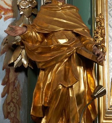 Zdjęcie nr 2: Rzeźba drążona z tyłu, ukazana frontalnie z głową skierowaną w prawo, w kontrapoście, o esowato wygiętej sylwetce. Lewa ręka świętego podtrzymuje księgę opartą na biodrze, prawa jest zgięta i uniesiona w bok. Twarz pociągła, o długim nosie, półprzymkniętych oczach zwróconych ku górze. Okolona jest krótką brodą oraz włosami z tonsurą na czubku głowy. Święty ubrany jest w habit oraz płaszcz zawinięty na prawej nodze. Habit o delikatnych załamaniach tkaniny, ściśle przylegający do ciała. Płaszcz głęboko rzeźbiony, silnie marszczony o grubych, ostrych fałdach. Polichromia naturalistyczna w partiach ciała, szaty złocone, atrybuty srebrzone.