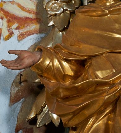 Zdjęcie nr 5: Rzeźba drążona z tyłu, ukazana frontalnie z głową skierowaną w prawo, w kontrapoście, o esowato wygiętej sylwetce. Lewa ręka świętego podtrzymuje księgę opartą na biodrze, prawa jest zgięta i uniesiona w bok. Twarz pociągła, o długim nosie, półprzymkniętych oczach zwróconych ku górze. Okolona jest krótką brodą oraz włosami z tonsurą na czubku głowy. Święty ubrany jest w habit oraz płaszcz zawinięty na prawej nodze. Habit o delikatnych załamaniach tkaniny, ściśle przylegający do ciała. Płaszcz głęboko rzeźbiony, silnie marszczony o grubych, ostrych fałdach. Polichromia naturalistyczna w partiach ciała, szaty złocone, atrybuty srebrzone.