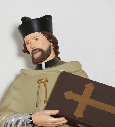 Zdjęcie nr 2: Rzeźba pełnoplastyczna, ustawiona na niskiej, nieregularnej podstawie i niewielkim prostopadłościennym postumencie umieszczonym na konsoli. Figura św. Jana Nepomucena jest zwrócona frontalnie, z głową przechyloną w prawo, w mocnym kontrapoście, o esowato wygiętej sylwetce. Święty w obu rękach zwróconych w lewo podtrzymuje księgę. Twarz ma okrągłą, o delikatnie zarysowanych oczach, szerokim nosie i otwartych ustach, okoloną brodą i krótkimi, kręconymi włosami. Święty ubrany jest w strój kanonika: czarną sutannę, posrebrzoną komżę oraz beżową almucję, na głowie ma czarny biret. Polichromia ciała naturalistyczna. 