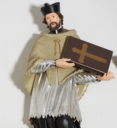 Zdjęcie nr 1: Rzeźba pełnoplastyczna, ustawiona na niskiej, nieregularnej podstawie i niewielkim prostopadłościennym postumencie umieszczonym na konsoli. Figura św. Jana Nepomucena jest zwrócona frontalnie, z głową przechyloną w prawo, w mocnym kontrapoście, o esowato wygiętej sylwetce. Święty w obu rękach zwróconych w lewo podtrzymuje księgę. Twarz ma okrągłą, o delikatnie zarysowanych oczach, szerokim nosie i otwartych ustach, okoloną brodą i krótkimi, kręconymi włosami. Święty ubrany jest w strój kanonika: czarną sutannę, posrebrzoną komżę oraz beżową almucję, na głowie ma czarny biret. Polichromia ciała naturalistyczna. 