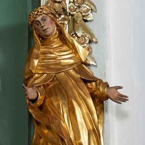 Zdjęcie nr 1: Rzeźba drążona z tyłu, ukazana frontalnie, z pochyloną głową i przechyloną w prawo sylwetką, obie ręce rozłożone na boki. Jej twarz jest okrągła, o głęboko osadzonych oczach skierowanych w dół, dużym nosie i delikatnie rozchylonych ustach. Święta jest ubrana w habit, płaszcz oraz welon z koroną cierniową na głowie. Tkanina sztywna, delikatnie łamana, płaszcz ekspresyjnie drapowany w grube fałdy. Polichromia w partiach ciała naturalistyczna, szaty pozłacane.