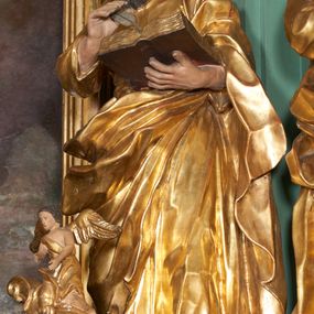 Zdjęcie nr 1: Rzeźba drążona z tyłu, zwrócona frontalnie z pochyloną głową, w kontrapoście, o esowato wygiętej sylwetce. Lewa ręka postaci ugięta podtrzymuje księgę na wysokości piersi, w prawej, uniesionej święty trzyma pióro. Twarz podłużna, zindywidualizowana, o długim nosie, oczach zwróconych w dół i delikatnie rozchylonych ustach; okolona długą brodą spływającą na pierś. Włosy krótkie, w postaci loków. Tunika ściśle przylegająca do ciała i delikatnie marszczona. Płaszcz przewieszony diagonalnie przez lewe ramię i zawieszony na prawym biodrze, w postaci ekspresyjnie rzeźbionej, obficie fałdowanej, ciężkiej tkaniny. Partie ciała i atrybuty polichromowane naturalistycznie, szaty złocone.