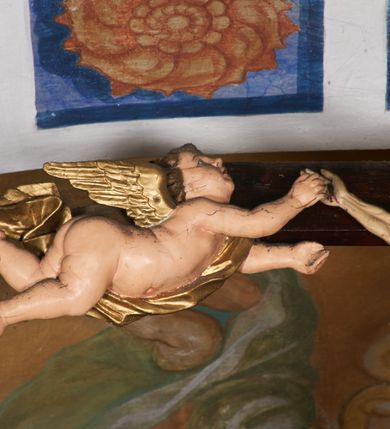 Zdjęcie nr 7: Belka tęczowa w formie łuku segmentowego nadwieszonego z krucyfiksem umieszczonym na środku, na profilowanym cokole. Do prostego krzyża przybita trzema gwoździami figura umarłego Chrystusa. Postać ukazana w lekkim zwisie, o szeroko rozłożonych ramionach, z głową opadającą na prawy bark, nogi lekko ugięte w kolanach. Twarz Chrystusa jest pociągła, szczupła, o głęboko osadzonych, zamkniętych oczach, długim, wąskim nosie i niewielkich ustach, okolona jest zarostem i długimi włosami w postaci wijących się pukli, opadających na plecy i ramiona. Na głowie korona cierniowa. Ciało o wyraźnie podkreślonej anatomii klatki piersiowej oraz muskulaturze ramion i nóg. Perizonium sięgające połowy ud, obficie fałdowane, zawiązane na lewym boku ze zwisem tkaniny. Ramiona poziomej belki krzyża podtrzymują małe, uskrzydlone aniołki, przepasane złotą tkaniną, zaś pionową, u spodu podtrzymuje nadlatujący anioł przedstawiony w pozycji półleżącej w silnie rozwianych i głęboko sfałdowanych szatach. Karnacja Chrystusa i aniołów malowana farbą olejną w kolorach naturalnych, perizonium białe, skrzydła i szaty aniołów pozłacane.