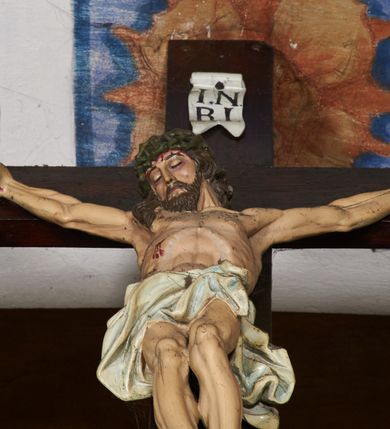 Zdjęcie nr 4: Belka tęczowa w formie łuku segmentowego nadwieszonego z krucyfiksem umieszczonym na środku, na profilowanym cokole. Do prostego krzyża przybita trzema gwoździami figura umarłego Chrystusa. Postać ukazana w lekkim zwisie, o szeroko rozłożonych ramionach, z głową opadającą na prawy bark, nogi lekko ugięte w kolanach. Twarz Chrystusa jest pociągła, szczupła, o głęboko osadzonych, zamkniętych oczach, długim, wąskim nosie i niewielkich ustach, okolona jest zarostem i długimi włosami w postaci wijących się pukli, opadających na plecy i ramiona. Na głowie korona cierniowa. Ciało o wyraźnie podkreślonej anatomii klatki piersiowej oraz muskulaturze ramion i nóg. Perizonium sięgające połowy ud, obficie fałdowane, zawiązane na lewym boku ze zwisem tkaniny. Ramiona poziomej belki krzyża podtrzymują małe, uskrzydlone aniołki, przepasane złotą tkaniną, zaś pionową, u spodu podtrzymuje nadlatujący anioł przedstawiony w pozycji półleżącej w silnie rozwianych i głęboko sfałdowanych szatach. Karnacja Chrystusa i aniołów malowana farbą olejną w kolorach naturalnych, perizonium białe, skrzydła i szaty aniołów pozłacane.