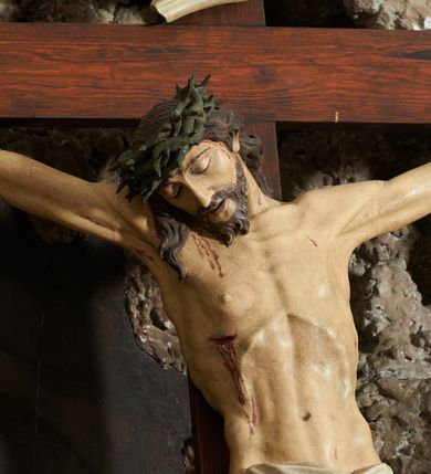 Zdjęcie nr 3: Krzyż zwrócony jest w trzech czwartych w lewo, lekko pochylony, na górnej belce krzyża zwój z napisem „I.N / R.I.”. Do niego przybita jest trzema gwoździami pełnoplastyczna rzeźba umarłego Chrystusa. Figura w delikatnym zwisie ciała o szeroko rozłożonych ramionach oraz łukowato wygiętej sylwetce, głowa opada bezwładnie na prawy bark, nogi lekko ugięte w kolanach, stopy skrzyżowane w układzie prawa na lewą. Twarz o łagodnych rysach, zamkniętych oczach, długim, prostym nosie oraz nieznacznie rozchylonych ustach, okolona krótką brodą. Włosy rzeźbione w silnie skręcone pukle opadające na ramię i plecy, na głowie korona cierniowa. Ciało silnie wychudzone z zaznaczonymi śladami męki, plastycznie modelowane, o wyraźnie podkreślonej muskulaturze ramion i ud oraz żeber klatki piersiowej. Perizonium w formie ekspresyjnie rozwianej, silnie drapowanej tkaniny, przewiązanej podwójnym sznurem, odsłaniającej prawe biodro, z obfitym zwisem na prawym biodrze. Polichromia naturalistyczna, karnacja bladobeżowa, włosy ciemnobrązowe, perizonium białe.