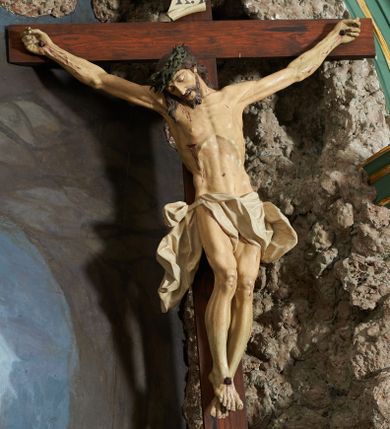 Zdjęcie nr 1: Krzyż zwrócony jest w trzech czwartych w lewo, lekko pochylony, na górnej belce krzyża zwój z napisem „I.N / R.I.”. Do niego przybita jest trzema gwoździami pełnoplastyczna rzeźba umarłego Chrystusa. Figura w delikatnym zwisie ciała o szeroko rozłożonych ramionach oraz łukowato wygiętej sylwetce, głowa opada bezwładnie na prawy bark, nogi lekko ugięte w kolanach, stopy skrzyżowane w układzie prawa na lewą. Twarz o łagodnych rysach, zamkniętych oczach, długim, prostym nosie oraz nieznacznie rozchylonych ustach, okolona krótką brodą. Włosy rzeźbione w silnie skręcone pukle opadające na ramię i plecy, na głowie korona cierniowa. Ciało silnie wychudzone z zaznaczonymi śladami męki, plastycznie modelowane, o wyraźnie podkreślonej muskulaturze ramion i ud oraz żeber klatki piersiowej. Perizonium w formie ekspresyjnie rozwianej, silnie drapowanej tkaniny, przewiązanej podwójnym sznurem, odsłaniającej prawe biodro, z obfitym zwisem na prawym biodrze. Polichromia naturalistyczna, karnacja bladobeżowa, włosy ciemnobrązowe, perizonium białe.
