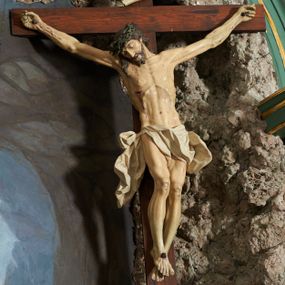 Zdjęcie nr 1: Krzyż zwrócony jest w trzech czwartych w lewo, lekko pochylony, na górnej belce krzyża zwój z napisem „I.N / R.I.”. Do niego przybita jest trzema gwoździami pełnoplastyczna rzeźba umarłego Chrystusa. Figura w delikatnym zwisie ciała o szeroko rozłożonych ramionach oraz łukowato wygiętej sylwetce, głowa opada bezwładnie na prawy bark, nogi lekko ugięte w kolanach, stopy skrzyżowane w układzie prawa na lewą. Twarz o łagodnych rysach, zamkniętych oczach, długim, prostym nosie oraz nieznacznie rozchylonych ustach, okolona krótką brodą. Włosy rzeźbione w silnie skręcone pukle opadające na ramię i plecy, na głowie korona cierniowa. Ciało silnie wychudzone z zaznaczonymi śladami męki, plastycznie modelowane, o wyraźnie podkreślonej muskulaturze ramion i ud oraz żeber klatki piersiowej. Perizonium w formie ekspresyjnie rozwianej, silnie drapowanej tkaniny, przewiązanej podwójnym sznurem, odsłaniającej prawe biodro, z obfitym zwisem na prawym biodrze. Polichromia naturalistyczna, karnacja bladobeżowa, włosy ciemnobrązowe, perizonium białe.