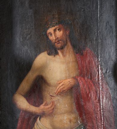 Zdjęcie nr 1: Obraz w formie stojącego prostokąta. Chrystus przedstawiony w półpostaci, zwrócony w trzech czwartych w lewo, z głową przechyloną na prawe ramię, obiema rękami wskazuje na ranę w prawym boku. Twarz podłużna, modelowana światłocieniem, o migdałowatych oczach, prostym nosie i pełnych ustach, okolona jasną, krótką brodą. Włosy brązowe, lekko kręcone, opadają na ramiona. Na głowie korona cierniowa. Chrystus w partii bioder przepasany białą, drapowaną tkaniną, na lewe ramię i plecy narzucony czerwony płaszcz. Ciało szczupłe, o miękkim modelunku światłocieniowym, delikatnie zarysowanym torsie, z zaznaczonymi śladami męki na dłoniach i prawym boku. Tło ciemnobrązowe, rozjaśnione wokół głowy postaci. Obraz utrzymany w ciepłej tonacji.