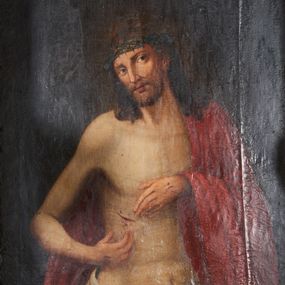 Zdjęcie nr 1: Obraz w formie stojącego prostokąta. Chrystus przedstawiony w półpostaci, zwrócony w trzech czwartych w lewo, z głową przechyloną na prawe ramię, obiema rękami wskazuje na ranę w prawym boku. Twarz podłużna, modelowana światłocieniem, o migdałowatych oczach, prostym nosie i pełnych ustach, okolona jasną, krótką brodą. Włosy brązowe, lekko kręcone, opadają na ramiona. Na głowie korona cierniowa. Chrystus w partii bioder przepasany białą, drapowaną tkaniną, na lewe ramię i plecy narzucony czerwony płaszcz. Ciało szczupłe, o miękkim modelunku światłocieniowym, delikatnie zarysowanym torsie, z zaznaczonymi śladami męki na dłoniach i prawym boku. Tło ciemnobrązowe, rozjaśnione wokół głowy postaci. Obraz utrzymany w ciepłej tonacji.