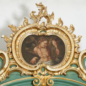 Zdjęcie nr 1: Obraz w formie powtarzającej kształt zwieńczenia, zbliżony do leżącego owalu. W centrum św. Sebastian ukazany w półpostaci, przywiązany do drzewa, zwrócony w trzech czwartych w lewo, z głową skierowaną w przeciwną stronę i opuszczoną w dół. Lewa ręka wysoko przywiązana do gałęzi sznurem, opada bezwładnie, prawa założona za gałąź. Twarz o młodzieńczych rysach, zmrużonych oczach, ostrym profilu nosa, okolona jasnobrązowymi włosami opadającymi na plecy. Tors odsłonięty, o wyraźnym modelunku silnie wychudzonego ciała z podkreśloną linią żeber, ze śladami męki i powbijanymi strzałami. Biodra przepasane białą tkaniną zawiązaną w partii podbrzusza. Tło jednolite ciemnobrązowe. Kolorystyka przygaszona, brunatna.