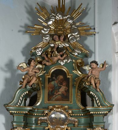 Zdjęcie nr 2: Nastawa ołtarzowa architektoniczna, jednoosiowa, jednokondygnacyjna ze zwieńczeniem, ustawiona na cokole, o lekko wklęsłym licu. Ołtarz prostopadłościenny, z drewnianą mensą. Antepedium dekorowane płyciną z monogramem Marii w wieńcu utworzonym z liści i kwiatów oraz stylizowanymi liśćmi w narożach. Nastawa ujęta parą pilastrów podtrzymujących belkowanie wyłamane na ich osi oraz odcinki falistego, przerwanego przyczółka, na którym siedzi para puttów. W polu środkowym płycina w profilowanej ramie w formie stojącego prostokąta zamkniętego łukiem odcinkowym nadwieszonym, wewnątrz obraz Matki Boskiej Różańcowej w formie stojącego prostokąta. Przed pilastrami figury św. Dominika i św. Katarzyny Sieneńskiej stojące na konsolach. Zwieńczenie w formie zbliżonej do stojącego prostokąta ujęte wolutami, zakończone faliście wygiętym gzymsem i glorią promienistą z monogramem IHS otoczonym obłokami, z główkami anielskimi i nadlatującym puttem. W polu obraz św. Józefa z Dzieciątkiem w kształcie stojącego prostokąta zamkniętego łukiem nadwieszonym półkolistym. Po bokach nastawy roślinne zwisy. Struktura polichromowana w kolorze jasnozielonym, profile oraz ornamentyka złocone.
Wewnątrz mensy napisy: „Glixelli / A. / za / Ks(iądz) Kan(onik) Aniołki / Ks(ądz) Wik(ary) Karkuli / Ks(iądz) Kat(echeta) Uczniuka / R(oku) P(ańskiego) / 1950 / Pozłotnicy z fir(my) / WIADROWSKIEGO / Najder M”.
