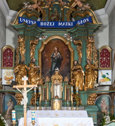 Zdjęcie nr 2: Nastawa ołtarzowa architektoniczna, jednoosiowa, jednokondygnacyjna ze zwieńczeniem, na dwustrefowym cokole. Ołtarz prostopadłościenny, mensa marmurowa z portatylem. Antepedium w formie leżącego prostokąta ujęte płyciną z monogramem Marii w akantowym wieńcu w centrum, w narożach rocaille. Retabulum ujęte parą filarów dźwigających pełne belkowanie przerwane nad polem środkowym, wyłamane partie podtrzymywane przez rokokowe konsole z uskrzydlonymi główkami anielskimi i kartuszami. Na belkowaniu zdwojony przerwany przyczółek z puttami. W polu środkowym obraz Matki Boskiej Niepokalanie Poczętej ujęty profilowaną ramą w formie stojącego prostokąta, zamkniętego łukiem nadwieszonym z uskokiem. Z dwóch stron filarów cztery figury ewangelistów ustawione na konsolach. Zwieńczenie w formie stojącego prostokąta, ujęte spływami wolutowymi, zamknięte fragmentem falistego gzymsu oraz glorią promienistą z otwartą księgą z napisem: „LIBER GENERTIONIS / JESU CHRISTI” pośród obłoków i główek anielskich oraz figurek puttów. W polu obraz św. Stanisława w formie stojącego prostokąta zamkniętego półkolistym łukiem nadwieszonym. Nastawa ujęta uszami utworzonymi z rocaille'u i róż. Struktura ołtarza polichromowana w kolorze jasnozielonym, z pozłacanymi profilami i ornamentyką oraz posrebrzoną glorią i detalami.