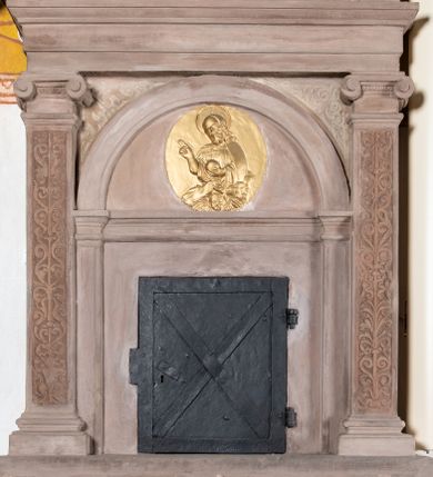 Zdjęcie nr 1: Sakramentarium architektoniczne, w formie aediculi, na podstawie przyjmującej kształt parapetu podtrzymywanego przez dwie konsole, pomiędzy którymi w kartuszu znajduje się rzeźbiony herb Prus I. Flankowane jest pilastrami o głowicach jońskich i trzonach dekorowanych rytą groteską, dźwigającymi pełne belkowanie z silnie wysuniętym gzymsem dekorowanym kostkowaniem. Fryz ze złoconą inskrypcją „ECCE PANIS ANGELORVUM”. W polu głównym znajduje się półkolista arkada  wsparta na toskańskich pilastrach, podzielona gzymsem na dwie części, w dolnej znajdują się kute drzwiczki w formie stojącego prostokąta, w górnej, w tympanonie pozłacany, owalny medalion z płaskorzeźbioną półpostacią błogosławiącego Chrystusa trzymającego kulę zwieńczoną krzyżem. W przyłuczach arkady ryta arabeska. Sakramentarium polichromowane w kolorze blado różowym z pozłacanymi detalami.

