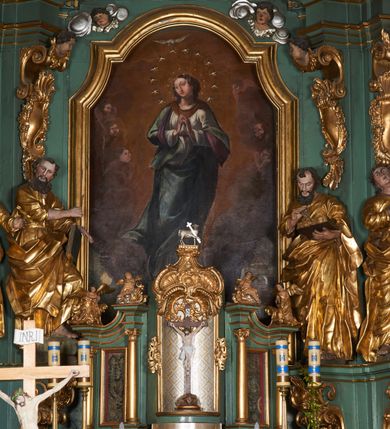 Zdjęcie nr 4: Tabernakulum w formie sześcianu, z wypukłym frontem. Drzwiczki w formie stojącego prostokąta zamkniętego łukiem półkolistym z aplikacją przedstawiającą kielich z hostią z monogramem IHS w glorii. Tron wystawienia architektoniczny, trójosiowy. Oś środkowa w postaci obrotowej niszy ujętej w profilowaną ramę, z konchą utworzoną z rocaille&#039;u, zakończona ornamentalnym zwieńczeniem dekorowanym muszlą, małżowiną i kartuszem, które tworzą postument dla rzeźby baranka z krzyżem. Osie boczne na cokole, cofniętym pod kątem w tył, ujęte dwiema parami kolumn różnej wysokości o kapitelach kompozytowych, dźwigających pełne belkowanie w formie spływu, wyłamane w ich partii, na których znajdują się siedzące i klęczące figury aniołów. Między kolumnami prostokątne płyciny z wotami. Struktura polichromowana w kolorze jasnozielonym z pozłoconymi profilami i ornamentyką.