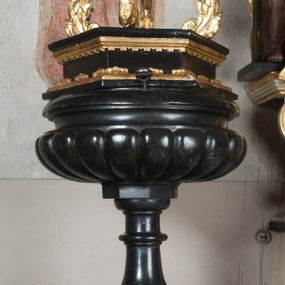 Zdjęcie nr 1: Chrzcielnica została osadzona na trójstopniowej, schodkowo zmniejszającej się, kwadratowej w rzucie podstawie. Jest utworzona z trzonu w typie gruszkowatym, który podtrzymuje płytką czarę, silnie wybrzuszoną w dolnej części, z puklami i lekko wklęsłą w górnej z profilowanym, zaoblonym brzegiem. Pokrywa drewniana,  sześcioboczna, zwieńczona czterema liściastymi, wolutowymi kabłąkami z kulą i krzyżem na szczycie. Na podstawie ryta inskrypcja:  "A[NDREAS] M[AJERANOWSKI] / PH[ILOSOPHIAE] D[OCTOR] / P[AROCHUS] G[IEBULTOVIENSIS] / D[EO] S[ACRUM] / A[NNO] D[OMINI] / 1666".