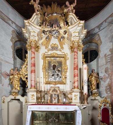 Zdjęcie nr 13: Nastawa ołtarzowa architektoniczna, jednoosiowa, jednokondygnacyjna ze zwieńczeniem z bramkami. Bramki z przejściami w formie stojącego prostokąta, zwieńczone fantazyjnym łukiem ujętym spływami wolutowymi, zakończonymi cokołami z figurami aniołów. Ołtarz kamienny w drewnianej obudowie z drewnianą mensą. Antepedium w formie leżącego prostokąta w profilowanej ramie, podzielone na pięć pól, w środkowym aplikowany monogram maryjny. Tabernakulum o wypukłej ścianie frontowej, ujęte w narożach ukośnie dostawionymi pilastrami o trzonach utworzonych z wolut. Drzwiczki w formie stojącego prostokąta zamkniętego łukiem wklęsło-wypukłym z uskokiem; w polu kielich z hostią w glorii. Tron wystawienia w formie zwężającego się ku górze cokołu o ściętych narożach, ujętych spływami wolutowymi. Z przodu owalny kartusz z monogramem IHS. Kondygnacja ustawiona na zdwojonym cokole, ujęta parą zwielokrotnionych pilastrów i parą kolumn wysuniętych do przodu o kapitelach kompozytowych, dźwigających imposty zwrócone do wewnątrz ołtarza oraz przerwany falisty przyczółek z siedzącą parą puttów. W polu środkowym profilowana rama w kształcie stojącego prostokąta z obrazem Matki Boskiej Częstochowskiej, na zasuwie obraz „Najświętsze Serce Jezusa”. Zwieńczenie w formie promienistej  glorii. W polu obłoki z otwartą księgą i uskrzydlonymi główkami anielskimi. Kondygnacja ujęta uszami utworzonymi z ażurowego ornamentu rocaille'owego z elementami wstęgi. Struktura polichromowana w kolorze beżowym, kolumny marmoryzowane w kolorze różowo-czerwonym, detale i ornamentyka złocone oraz srebrzone.