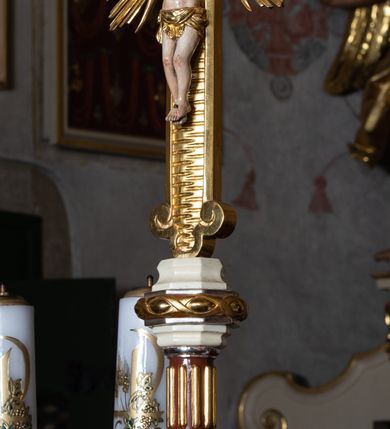 Zdjęcie nr 18: Nastawa ołtarzowa architektoniczna, jednoosiowa, jednokondygnacyjna ze zwieńczeniem z bramkami. Bramki z przejściami w formie stojącego prostokąta, zwieńczone fantazyjnym łukiem ujętym spływami wolutowymi, zakończonymi cokołami z figurami aniołów. Ołtarz kamienny w drewnianej obudowie z drewnianą mensą. Antepedium w formie leżącego prostokąta w profilowanej ramie, podzielone na pięć pól, w środkowym aplikowany monogram maryjny. Tabernakulum o wypukłej ścianie frontowej, ujęte w narożach ukośnie dostawionymi pilastrami o trzonach utworzonych z wolut. Drzwiczki w formie stojącego prostokąta zamkniętego łukiem wklęsło-wypukłym z uskokiem; w polu kielich z hostią w glorii. Tron wystawienia w formie zwężającego się ku górze cokołu o ściętych narożach, ujętych spływami wolutowymi. Z przodu owalny kartusz z monogramem IHS. Kondygnacja ustawiona na zdwojonym cokole, ujęta parą zwielokrotnionych pilastrów i parą kolumn wysuniętych do przodu o kapitelach kompozytowych, dźwigających imposty zwrócone do wewnątrz ołtarza oraz przerwany falisty przyczółek z siedzącą parą puttów. W polu środkowym profilowana rama w kształcie stojącego prostokąta z obrazem Matki Boskiej Częstochowskiej, na zasuwie obraz „Najświętsze Serce Jezusa”. Zwieńczenie w formie promienistej  glorii. W polu obłoki z otwartą księgą i uskrzydlonymi główkami anielskimi. Kondygnacja ujęta uszami utworzonymi z ażurowego ornamentu rocaille'owego z elementami wstęgi. Struktura polichromowana w kolorze beżowym, kolumny marmoryzowane w kolorze różowo-czerwonym, detale i ornamentyka złocone oraz srebrzone.
