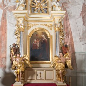 Zdjęcie nr 1: Ołtarz architektoniczny, przyścienny, jednoosiowy, jednokondygnacyjny, ze zwieńczeniem. Ołtarz drewniany, prostopadłościenny. Antepedium w kształcie leżącego prostokąta, ujęte profilowaną ramą, w polu płaskorzeźbiony grecki krzyżyk, a w narożach stylizowane wici akantu. W część cokołową wbudowane tabernakulum, z drzwiczkami ozdobionymi płaskorzeźbionym kielichem z hostią. Nastawa ustawiona na wysokim cokole, ujęta kolumnami o gładkich, posrebrzanych trzonach, z głowicami kompozytowymi, które podtrzymują silnie wysunięte do przodu wyłamane belkowanie ze wspólnym, bogato profilowanym, wysuniętym do przodu gzymsem. Na osi kolumn ponad gzymsem wolutowe przyczółki, na których siedzą uskrzydlone putta. W polu środkowym obraz w kształcie stojącego prostokąta, zamknięty łukiem nadwieszonym, ujęty w profilowaną ramę z przedstawieniem św. Anny Samotrzeć. Z przodu na tle kolumn ustawione dwie wolnostojące figury aniołów o złoconych skrzydłach i szatach. Po zewnętrznych stronach kolumn, na konsolach usadowione figury św. Józefa (po lewej) oraz św. Joachima (po prawej). Kondygnacja ujęta uszami ze stylizowanego ornamentu akantowego. 
Zwieńczenie flankowane półkolumnami o kompozytowych kapitelach podtrzymujących profilowany gzyms przybierający kształt dwóch stykających się wolut, zwieńczony muszlą palmetową i krzyżem. W polu zwieńczenia ażurowy prześwit w kształcie prostokąta o uskokowo i ćwierćkoliście ściętych narożach, wypełniony okiem Opatrzności na tle promienistej glorii. Struktura polichromowana w kolorze jasnego beżu, ornamentyka oraz detale złocone i srebrzone.
