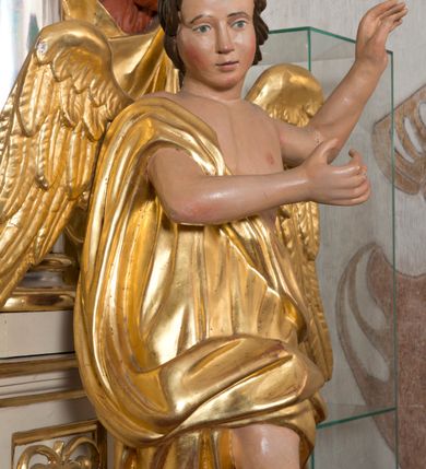 Zdjęcie nr 7: Rzeźby wolnostojące, ścięte z tyłu, drążone; ustawione na zdwojonych, niskich cokołach, stojących na czterech płaskich nóżkach. Figury ustawione w kontrapoście o ożywionych pozach z rękami uniesionymi do góry. Twarze młodzieńcze o spokojnych, podobnych rysach; włosy średniej długości, falowane, zasłaniające uszy. Figury ubrane w złote szaty, mocno drapowane, odsłaniające jedno ramię. Polichromia ciała naturalistyczna, szaty i skrzydła złocone. 