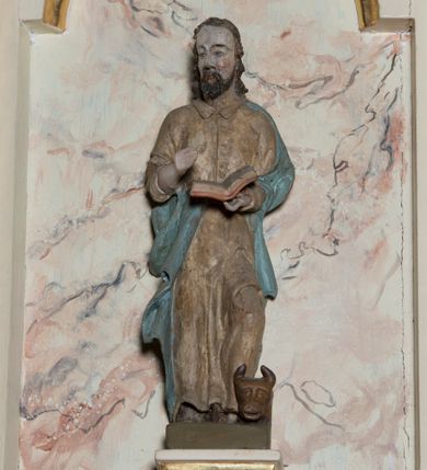 Zdjęcie nr 5: Ambona przyścienna, wisząca, z dostępem schodkami z lewej strony. Podwieszenie ośmioboczne, zwężające się ku dołowi, zakończone trzema spiętymi kabłąkami. Kosz na planie ośmioboku ze ściankami oddzielonymi półkolumnami, pomiędzy którymi płyciny w formie stojącego prostokąta zamkniętego łukiem nadwieszonym. W polach płycin, na cokołach ustawione figury ewangelistów i Chrystusa Salwatora. Od lewej: św. Jan, św. Marek, św. Łukasz i Chrystus Salwator. Ewangeliści z księgami w dłoniach, Chrystus z jabłkiem królewskim. Ubrani są w długie suknie i płaszcze przewieszone przez jedno ramię. Parapet w formie niepełnego belkowania z wyłamanym gzymsem Schody jednobiegowe, ośmiostopniowe z balustradą o tralkach w kształcie skręconych kolumn. Ambona polichromowana na beżowo, ze złoconymi i srebrzonymi detalami. Tło płycin zdobione imitacją marmoryzacji.