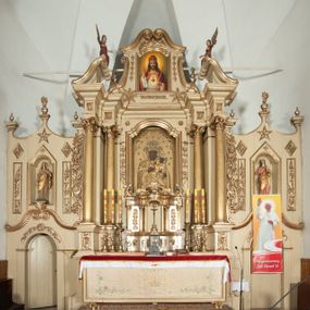 Zdjęcie nr 1: Ołtarz architektoniczny, jednokondygnacyjny, trójosiowy, ze zwieńczeniem. Ołtarz prostopadłościenny, z drewnianą mensą. Antepedium w formie haftowanej tkaniny zdobionej po środku motywem zwieńczonego krzyżem monogramu maryjnego z koroną, ujętego dwunastoma gwiazdami, natomiast w dolnych narożach gałązkami z kwiatami białych lilii.  Tabernakulum z tronem wystawienia w formie jednokondygnacyjnej, trójosiowej bryły architektonicznej, osadzonej na wysokim cokole. Tabernakulum wbudowane w osi środkowej cokołu, drzwiczki prostokątne, zdobione płaskorzeźbionym motywem kielicha eucharystycznego. Flankowane po skrajnych bokach parą pilastrów osie boczne całej struktury są wklęsłe i cofnięte względem osi środkowej ujętej parą kolumienek. Podpory wspierają wyłamujące się ponad nimi belkowanie z gzymsem po środku w formie łuku koszowego. Część środkowa w formie niszy zamkniętej motywem konchy. W zwieńczeniu figurka baranka paschalnego ujętego promienistą glorią, ukazanego na owalnej podstawie osadzonej na 4 wolutowych kabłąkach. Po bokach para figur adorujących aniołów. Cokół zdobiony motywami uskrzydlonych główek anielskich, rocaille’i oraz gałązek z kiściami winnej latorośli. Pola osi bocznych wypełnia para podwieszeń w formie gałązek różanych, partie fryzu pojedyncze rozetki. Struktura tabernakulum i tronu wystawienia jest złocona i srebrzona.   Retabulum osadzone na zdwojonym, zryzalitowanym uskokowo po bokach cokole. Część środkowa ujęta dwoma parami kolumn – wewnętrzne ustawione na tle pary pilastrów, zewnętrzne na tle pary filarów. Podpory dźwigają wyłamujące się ponad nimi belkowanie przerwane w partii architrawu i fryzu. Zwieńczenie ujęte parą spływów wolutowych, zamknięte parą stykających się wolut. Po bokach przerwany, wolutowy przyczółek. W dolnych polach osi bocznych retabulum para półkoliście zamkniętych bramek, ujętych prostą arkadą. Pola osi oddzielone parami stykających się wolut zwieńczonych konchą. W górnej strefie para płytkich niszy zamkniętych półkolistymi łukami nadwieszonymi i dodatkowo ujęta prostym, trójkątnie zamkniętym obramieniem. Osie zwieńczone trzema fragmentami gzymsu oddzielonymi parami wklęsłości.  Pola cokołu osi środkowej retabulum wypełnione ornamentyką roślinną. Część środkowa ujęta parą ażurowych, ornamentalnych  uszaków. Po bokach pola para zwisów w postaci gałązek różanych, w górnych narożach para rozetek. Pola fryzu zdobione rozetami. Pole zwieńczenia w górnej partii dekorowane parą ulistnionych gałązek, po bokach parą kampanuli, dołem w narożach para dużych rozet, pośrodku wić roślinna. Na spływach wolutowych para płomienistych wazonów, a na przyczółku para figur aniołów. Nadłucza bramek osi bocznych zdobione ornamentem roślinnym, nisze ujęte parą stylizowanych kandelabrów, wyżej para rombów z rozetami, pośrodku gwiazda. Na gzymsach wieńczących płomieniste wazony. W polu środkowym obraz w kształcie stojącego prostokąta zamkniętego odcinkowym łukiem nadwieszonym z uskokami, z wizerunkiem Madonny z Dzieciątkiem. W zwieńczeniu obraz w kształcie stojącego prostokąta zamkniętego odcinkowym łukiem nadwieszonym z uskokami, z wizerunkiem Chrystusa Króla. Nisze osi bocznych wypełniają figury, po prawej stronie św. Barbary, po lewej nieznanej świętej. Struktura w kolorze beżowym, detal architektoniczny i ornamentyka złocone.     