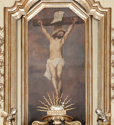 Zdjęcie nr 21: Ołtarz architektoniczny, jednokondygnacyjny, trójosiowy, ze zwieńczeniem. Ołtarz prostopadłościenny, z drewnianą mensą. Antepedium w formie haftowanej tkaniny zdobionej po środku motywem zwieńczonego krzyżem monogramu maryjnego z koroną, ujętego dwunastoma gwiazdami, natomiast w dolnych narożach gałązkami z kwiatami białych lilii.  Tabernakulum z tronem wystawienia w formie jednokondygnacyjnej, trójosiowej bryły architektonicznej, osadzonej na wysokim cokole. Tabernakulum wbudowane w osi środkowej cokołu, drzwiczki prostokątne, zdobione płaskorzeźbionym motywem kielicha eucharystycznego. Flankowane po skrajnych bokach parą pilastrów osie boczne całej struktury są wklęsłe i cofnięte względem osi środkowej ujętej parą kolumienek. Podpory wspierają wyłamujące się ponad nimi belkowanie z gzymsem po środku w formie łuku koszowego. Część środkowa w formie niszy zamkniętej motywem konchy. W zwieńczeniu figurka baranka paschalnego ujętego promienistą glorią, ukazanego na owalnej podstawie osadzonej na 4 wolutowych kabłąkach. Po bokach para figur adorujących aniołów. Cokół zdobiony motywami uskrzydlonych główek anielskich, rocaille’i oraz gałązek z kiściami winnej latorośli. Pola osi bocznych wypełnia para podwieszeń w formie gałązek różanych, partie fryzu pojedyncze rozetki. Struktura tabernakulum i tronu wystawienia jest złocona i srebrzona.   Retabulum osadzone na zdwojonym, zryzalitowanym uskokowo po bokach cokole. Część środkowa ujęta dwoma parami kolumn – wewnętrzne ustawione na tle pary pilastrów, zewnętrzne na tle pary filarów. Podpory dźwigają wyłamujące się ponad nimi belkowanie przerwane w partii architrawu i fryzu. Zwieńczenie ujęte parą spływów wolutowych, zamknięte parą stykających się wolut. Po bokach przerwany, wolutowy przyczółek. W dolnych polach osi bocznych retabulum para półkoliście zamkniętych bramek, ujętych prostą arkadą. Pola osi oddzielone parami stykających się wolut zwieńczonych konchą. W górnej strefie para płytkich niszy zamkniętych półkolistymi łukami nadwieszonymi i dodatkowo ujęta prostym, trójkątnie zamkniętym obramieniem. Osie zwieńczone trzema fragmentami gzymsu oddzielonymi parami wklęsłości.  Pola cokołu osi środkowej retabulum wypełnione ornamentyką roślinną. Część środkowa ujęta parą ażurowych, ornamentalnych  uszaków. Po bokach pola para zwisów w postaci gałązek różanych, w górnych narożach para rozetek. Pola fryzu zdobione rozetami. Pole zwieńczenia w górnej partii dekorowane parą ulistnionych gałązek, po bokach parą kampanuli, dołem w narożach para dużych rozet, pośrodku wić roślinna. Na spływach wolutowych para płomienistych wazonów, a na przyczółku para figur aniołów. Nadłucza bramek osi bocznych zdobione ornamentem roślinnym, nisze ujęte parą stylizowanych kandelabrów, wyżej para rombów z rozetami, pośrodku gwiazda. Na gzymsach wieńczących płomieniste wazony. W polu środkowym obraz w kształcie stojącego prostokąta zamkniętego odcinkowym łukiem nadwieszonym z uskokami, z wizerunkiem Madonny z Dzieciątkiem. W zwieńczeniu obraz w kształcie stojącego prostokąta zamkniętego odcinkowym łukiem nadwieszonym z uskokami, z wizerunkiem Chrystusa Króla. Nisze osi bocznych wypełniają figury, po prawej stronie św. Barbary, po lewej nieznanej świętej. Struktura w kolorze beżowym, detal architektoniczny i ornamentyka złocone.     