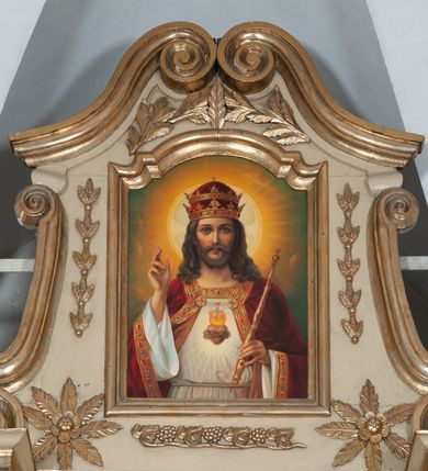 Zdjęcie nr 23: Ołtarz architektoniczny, jednokondygnacyjny, trójosiowy, ze zwieńczeniem. Ołtarz prostopadłościenny, z drewnianą mensą. Antepedium w formie haftowanej tkaniny zdobionej po środku motywem zwieńczonego krzyżem monogramu maryjnego z koroną, ujętego dwunastoma gwiazdami, natomiast w dolnych narożach gałązkami z kwiatami białych lilii.  Tabernakulum z tronem wystawienia w formie jednokondygnacyjnej, trójosiowej bryły architektonicznej, osadzonej na wysokim cokole. Tabernakulum wbudowane w osi środkowej cokołu, drzwiczki prostokątne, zdobione płaskorzeźbionym motywem kielicha eucharystycznego. Flankowane po skrajnych bokach parą pilastrów osie boczne całej struktury są wklęsłe i cofnięte względem osi środkowej ujętej parą kolumienek. Podpory wspierają wyłamujące się ponad nimi belkowanie z gzymsem po środku w formie łuku koszowego. Część środkowa w formie niszy zamkniętej motywem konchy. W zwieńczeniu figurka baranka paschalnego ujętego promienistą glorią, ukazanego na owalnej podstawie osadzonej na 4 wolutowych kabłąkach. Po bokach para figur adorujących aniołów. Cokół zdobiony motywami uskrzydlonych główek anielskich, rocaille’i oraz gałązek z kiściami winnej latorośli. Pola osi bocznych wypełnia para podwieszeń w formie gałązek różanych, partie fryzu pojedyncze rozetki. Struktura tabernakulum i tronu wystawienia jest złocona i srebrzona.   Retabulum osadzone na zdwojonym, zryzalitowanym uskokowo po bokach cokole. Część środkowa ujęta dwoma parami kolumn – wewnętrzne ustawione na tle pary pilastrów, zewnętrzne na tle pary filarów. Podpory dźwigają wyłamujące się ponad nimi belkowanie przerwane w partii architrawu i fryzu. Zwieńczenie ujęte parą spływów wolutowych, zamknięte parą stykających się wolut. Po bokach przerwany, wolutowy przyczółek. W dolnych polach osi bocznych retabulum para półkoliście zamkniętych bramek, ujętych prostą arkadą. Pola osi oddzielone parami stykających się wolut zwieńczonych konchą. W górnej strefie para płytkich niszy zamkniętych półkolistymi łukami nadwieszonymi i dodatkowo ujęta prostym, trójkątnie zamkniętym obramieniem. Osie zwieńczone trzema fragmentami gzymsu oddzielonymi parami wklęsłości.  Pola cokołu osi środkowej retabulum wypełnione ornamentyką roślinną. Część środkowa ujęta parą ażurowych, ornamentalnych  uszaków. Po bokach pola para zwisów w postaci gałązek różanych, w górnych narożach para rozetek. Pola fryzu zdobione rozetami. Pole zwieńczenia w górnej partii dekorowane parą ulistnionych gałązek, po bokach parą kampanuli, dołem w narożach para dużych rozet, pośrodku wić roślinna. Na spływach wolutowych para płomienistych wazonów, a na przyczółku para figur aniołów. Nadłucza bramek osi bocznych zdobione ornamentem roślinnym, nisze ujęte parą stylizowanych kandelabrów, wyżej para rombów z rozetami, pośrodku gwiazda. Na gzymsach wieńczących płomieniste wazony. W polu środkowym obraz w kształcie stojącego prostokąta zamkniętego odcinkowym łukiem nadwieszonym z uskokami, z wizerunkiem Madonny z Dzieciątkiem. W zwieńczeniu obraz w kształcie stojącego prostokąta zamkniętego odcinkowym łukiem nadwieszonym z uskokami, z wizerunkiem Chrystusa Króla. Nisze osi bocznych wypełniają figury, po prawej stronie św. Barbary, po lewej nieznanej świętej. Struktura w kolorze beżowym, detal architektoniczny i ornamentyka złocone.     