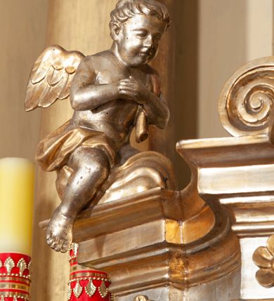 Zdjęcie nr 9: Ołtarz architektoniczny, jednokondygnacyjny, trójosiowy, ze zwieńczeniem. Ołtarz prostopadłościenny, z drewnianą mensą. Antepedium w formie haftowanej tkaniny zdobionej po środku motywem zwieńczonego krzyżem monogramu maryjnego z koroną, ujętego dwunastoma gwiazdami, natomiast w dolnych narożach gałązkami z kwiatami białych lilii.  Tabernakulum z tronem wystawienia w formie jednokondygnacyjnej, trójosiowej bryły architektonicznej, osadzonej na wysokim cokole. Tabernakulum wbudowane w osi środkowej cokołu, drzwiczki prostokątne, zdobione płaskorzeźbionym motywem kielicha eucharystycznego. Flankowane po skrajnych bokach parą pilastrów osie boczne całej struktury są wklęsłe i cofnięte względem osi środkowej ujętej parą kolumienek. Podpory wspierają wyłamujące się ponad nimi belkowanie z gzymsem po środku w formie łuku koszowego. Część środkowa w formie niszy zamkniętej motywem konchy. W zwieńczeniu figurka baranka paschalnego ujętego promienistą glorią, ukazanego na owalnej podstawie osadzonej na 4 wolutowych kabłąkach. Po bokach para figur adorujących aniołów. Cokół zdobiony motywami uskrzydlonych główek anielskich, rocaille’i oraz gałązek z kiściami winnej latorośli. Pola osi bocznych wypełnia para podwieszeń w formie gałązek różanych, partie fryzu pojedyncze rozetki. Struktura tabernakulum i tronu wystawienia jest złocona i srebrzona.   Retabulum osadzone na zdwojonym, zryzalitowanym uskokowo po bokach cokole. Część środkowa ujęta dwoma parami kolumn – wewnętrzne ustawione na tle pary pilastrów, zewnętrzne na tle pary filarów. Podpory dźwigają wyłamujące się ponad nimi belkowanie przerwane w partii architrawu i fryzu. Zwieńczenie ujęte parą spływów wolutowych, zamknięte parą stykających się wolut. Po bokach przerwany, wolutowy przyczółek. W dolnych polach osi bocznych retabulum para półkoliście zamkniętych bramek, ujętych prostą arkadą. Pola osi oddzielone parami stykających się wolut zwieńczonych konchą. W górnej strefie para płytkich niszy zamkniętych półkolistymi łukami nadwieszonymi i dodatkowo ujęta prostym, trójkątnie zamkniętym obramieniem. Osie zwieńczone trzema fragmentami gzymsu oddzielonymi parami wklęsłości.  Pola cokołu osi środkowej retabulum wypełnione ornamentyką roślinną. Część środkowa ujęta parą ażurowych, ornamentalnych  uszaków. Po bokach pola para zwisów w postaci gałązek różanych, w górnych narożach para rozetek. Pola fryzu zdobione rozetami. Pole zwieńczenia w górnej partii dekorowane parą ulistnionych gałązek, po bokach parą kampanuli, dołem w narożach para dużych rozet, pośrodku wić roślinna. Na spływach wolutowych para płomienistych wazonów, a na przyczółku para figur aniołów. Nadłucza bramek osi bocznych zdobione ornamentem roślinnym, nisze ujęte parą stylizowanych kandelabrów, wyżej para rombów z rozetami, pośrodku gwiazda. Na gzymsach wieńczących płomieniste wazony. W polu środkowym obraz w kształcie stojącego prostokąta zamkniętego odcinkowym łukiem nadwieszonym z uskokami, z wizerunkiem Madonny z Dzieciątkiem. W zwieńczeniu obraz w kształcie stojącego prostokąta zamkniętego odcinkowym łukiem nadwieszonym z uskokami, z wizerunkiem Chrystusa Króla. Nisze osi bocznych wypełniają figury, po prawej stronie św. Barbary, po lewej nieznanej świętej. Struktura w kolorze beżowym, detal architektoniczny i ornamentyka złocone.     