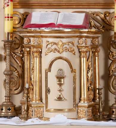 Zdjęcie nr 27: Ołtarz architektoniczny, jednokondygnacyjny, jednoosiowy ze zwieńczeniem. Ołtarz prostopadłościenny, z drewnianą mensą, z antepedium ujętym po bokach parą konsoli w formie wolut. Pole antepedium w postaci prostokątnej płyciny z płaskorzeźbionym motywem gorejącego serca pośrodku, ujętego promienistą glorią. Na mensie tabernakulum w formie prostopadłościennej szafki o wypukłej, przedniej  ściance ujętej dwoma parami osadzonych na niewielkich cokołach kolumienek wspierających niepełne, wyłamujące się ponad nimi belkowanie. Drzwiczki w kształcie stojącego prostokąta zamkniętego półkolistym łukiem nadwieszonym, zdobione motywem płaskorzeźbionego kielicha eucharystycznego. Struktura zdobiona motywami rozet i wici roślinnej. Retabulum osadzone na niewysokim, zryzalitowanym po bokach cokole. Część środkową nastawy ujmuje para ustawionych skośnie  filarów wspierających wyłamujące się ponad nimi belkowanie. Zamknięte półkoliście zwieńczenie ujmuje para spływów wolutowych oraz flankuje przerwany, wolutowy przyczółek. Pola wolutowych konsoli zdobi para liści akantu, cokół retabulum para stylizowanych słoneczników i S-kształtnych wici. Zewnętrzne pola trzonów filarów zdobią w górnych partiach ukwiecone gałązki, wewnętrzne motyw podwieszeń skomponowanych z zamkniętej korony, krzyżujących się rogów obfitości i krzyża z kotwicą, oraz kokard, u dołu para gałązek. Boki pola środkowego z motywem wici winnego grona, u góry w narożach para ulistnionych rozet. Fryz zdobiony rozetami, pośrodku kartusz w monogramem imienia Jezus ujętym parą gałązek laurowych. Retabulum flankowane parą ażurowych uszaków rocaille’owych. W dolnej partii zwieńczenia uskrzydlona główka anielska, szczyt w formie konchy ujętej po bokach parą rocaille’i. Na przerwanym przyczółku para figur aniołków. Pole części środkowej w kształcie stojącego prostokąta zamkniętego półkolistym łukiem nadwieszonym z uskokami, ujęte profilowaną, złoconą ramą, w środku wizerunek Najświętszego Serca Jezusa. Po bokach, na tle filarów para figur, po lewej św. Szczepan, po prawej św. Wawrzyniec. W zwieńczeniu obraz w kształcie trapezu o wklęsłych ramionach, podstawie i dolnych narożach, zamknięty półkolistym łukiem nadwieszonym, ujęty profilowaną, złoconą ramą, z wizerunkiem św. Katarzyny Aleksandryjskiej. 
Struktura w kolorze kremowym, detal architektoniczny i ornamentyka złocone.    
